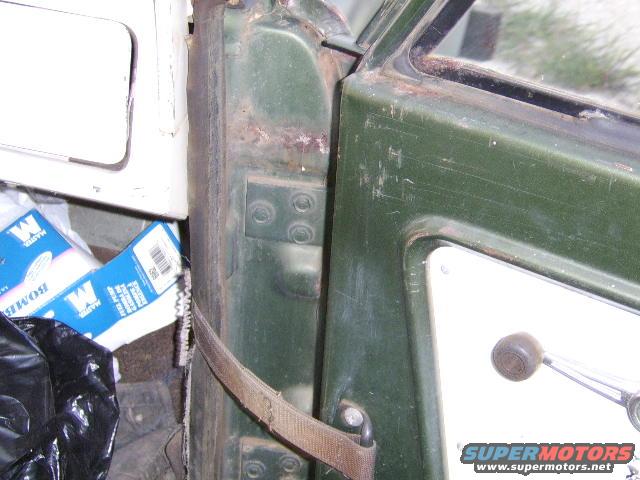 close-up of a green vehicle door jamb with a seatbelt and some items on the floor