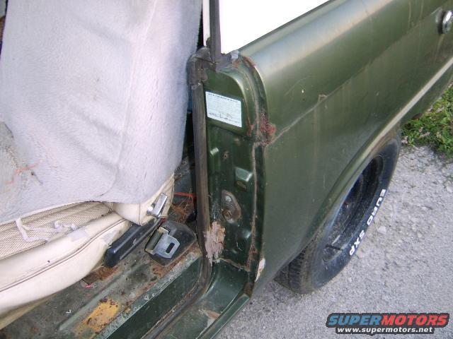 close-up of green vehicle's interior door frame, showing rust and a worn seat