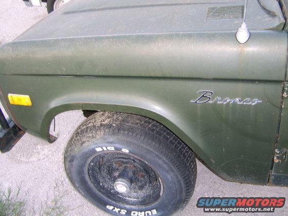 Green 1976 Ford Bronco, front fender and tire visible, dusty condition
