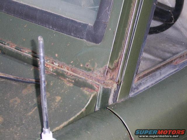 Green 1976 Ford Bronco interior corner showing rust around windshield frame