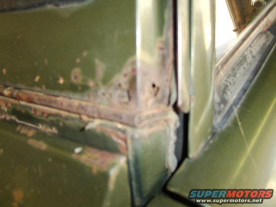 Green vehicle body corner showing significant rust damage around the door frame and window seal
