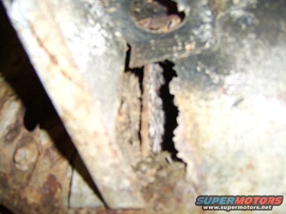 Close-up of heavily rusted metal frame with visible holes and damage