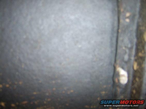 Close-up of textured metal surface with visible rust spots and a bolt