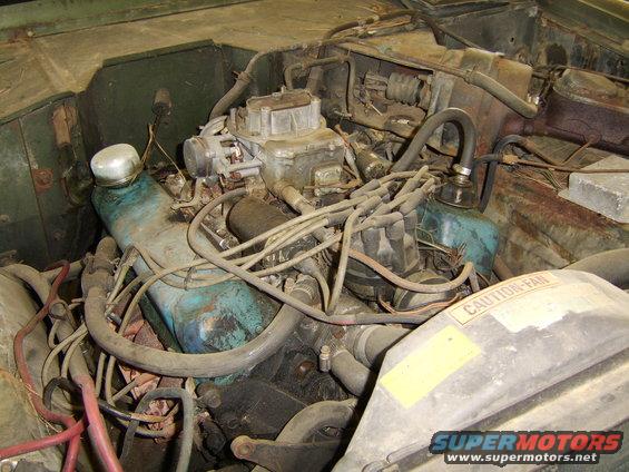 engine bay with carburetor, distributor, and fan shroud with caution label