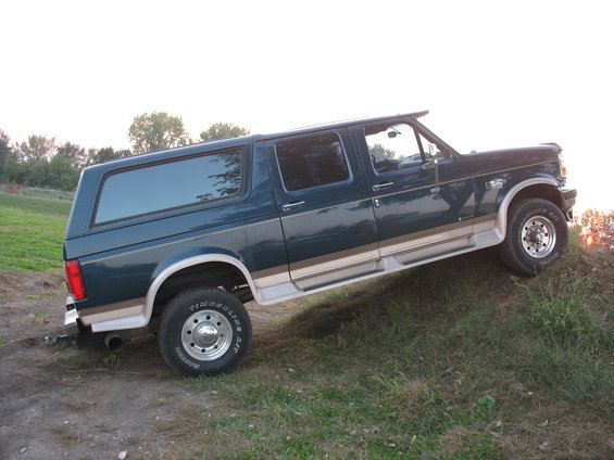 Dark green 1995 Ford C-350 Centurion Conversions extended SUV, tan trim, side view