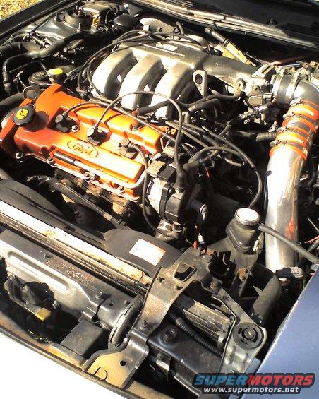 Engine bay of a 1994 Ford Probe, showing the V6 engine with orange valve covers and aftermarket intake