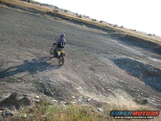Yellow dirt bike with rider on a gravelly hill