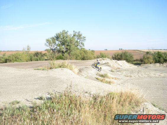 Dirt bike rider mid-air over a jump on a sunny day
