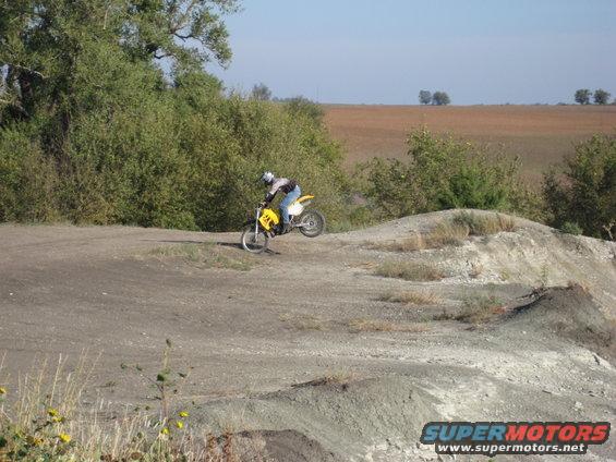 Yellow dirt bike with rider on a dirt track, side view