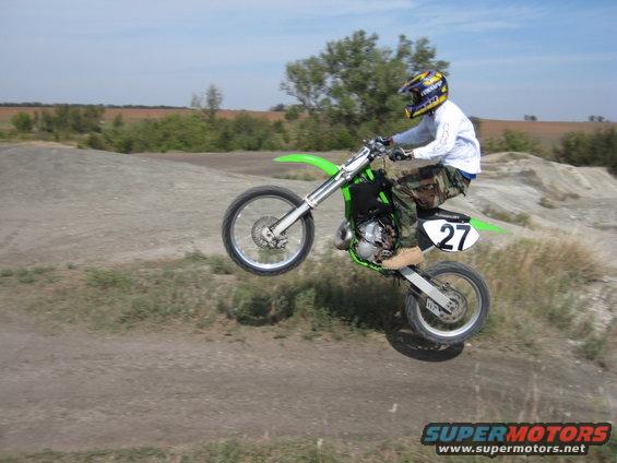 Green dirt bike with rider in mid-air, number 27 on rear fender