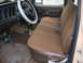 1978 Ford F-250 - The interior of a vintage truck features a brown bench seat and a white steering wheel cover.