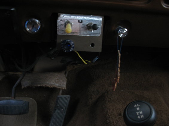 Interior shot of a vehicle's dashboard with a custom control panel, ignition, and a 4x4 gear shifter