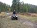 2008 Honda RANCHER - A person rides an ATV through a muddy, wooded trail, with another ATV visible in the distance.