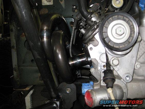 Engine manifold pipes and a serpentine belt pulley on a vehicle engine