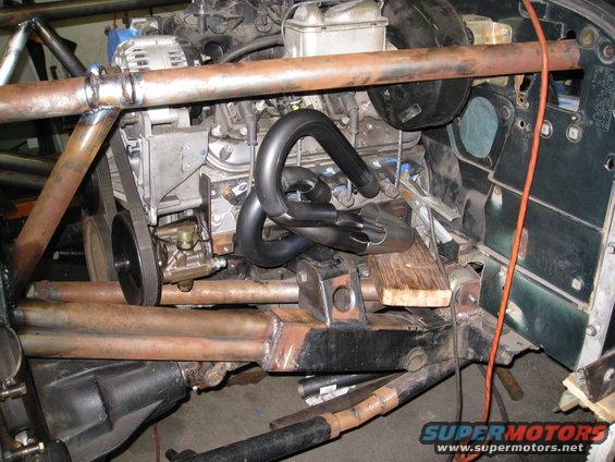 Custom vehicle with engine swap, showing exhaust headers and engine block