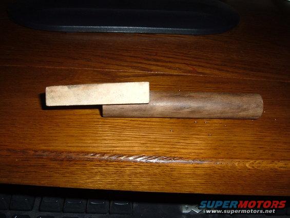 Wooden dowel with a rectangular block attached to one end, resting on a wooden surface