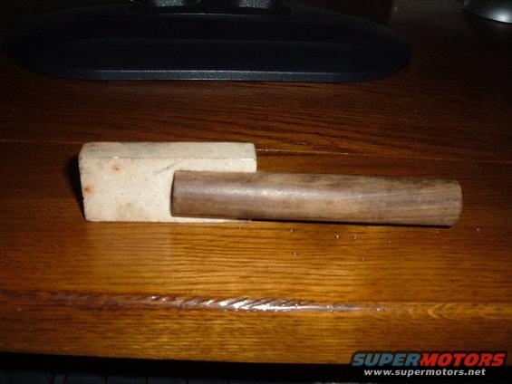Wooden handle inserted into a light-colored block, resting on a wooden surface