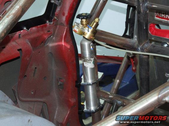 Interior of a modified car with a roll cage and a mounted CO2 tank. Red metal structure visible