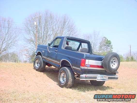 1989 Ford Bronco parked on a dirt hill, rear view with spare tire mounted on the back