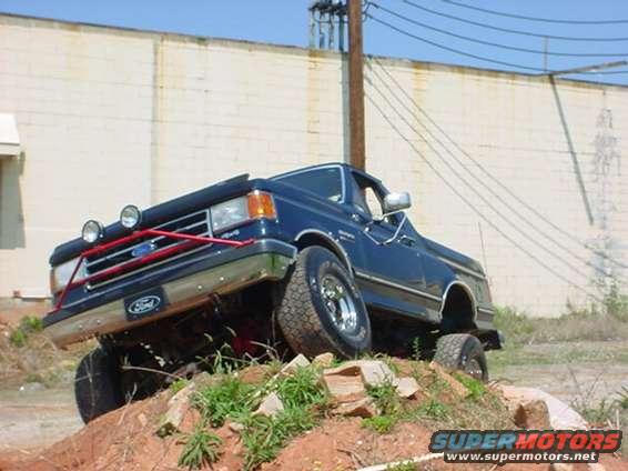 Blue Ford F-Series truck on a dirt hill with a red brush guard