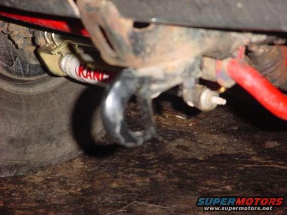 Close-up of a red suspension component and a white shock absorber with red lettering on an undercarriage