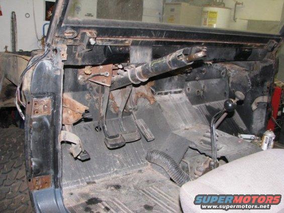 vehicle interior showing pedals, steering column, and shifter; appears to be undergoing restoration