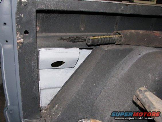 Vehicle interior showing a metal bracket with a hole and a rubber hose inside a metal tube