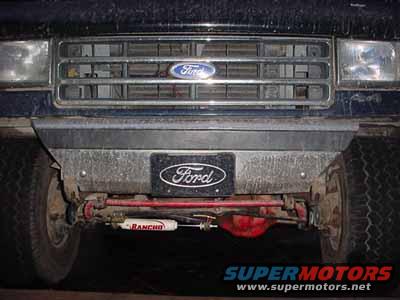 Ford Bronco front end with grille, bumper, and suspension components visible. Dark blue paint