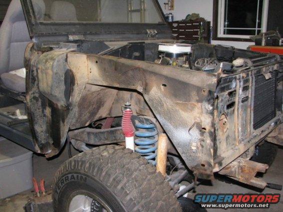 1976 Ford Bronco under repair, front quarter view, showing disassembled front end and engine bay