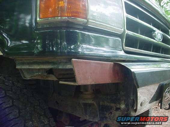 Front bumper corner of a dark green 1989 Ford Bronco with a red tow hook attachment