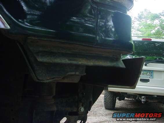 Close-up of vehicle frame and bumper with another vehicle in the background