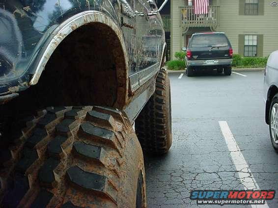Close-up of a large, mud-covered off-road tire and fender