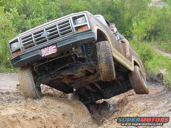 Brown 1980s Ford Bronco with front wheel stuck in mud