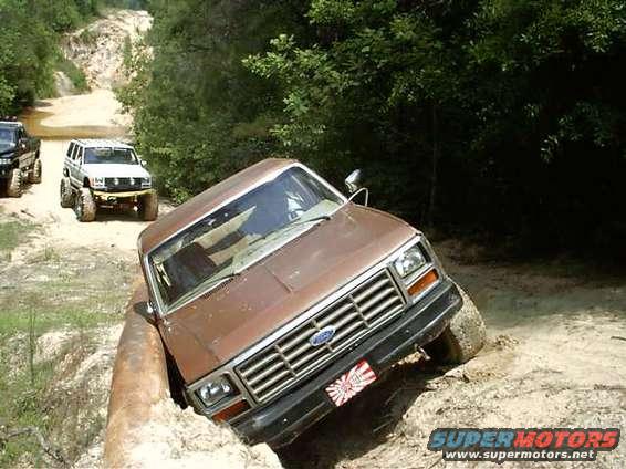 Brown 1980s Ford Bronco tilted in a ditch off-road