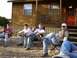 1983 Ford F-250 - Four young men relax in camping chairs in front of a rustic wooden cabin.