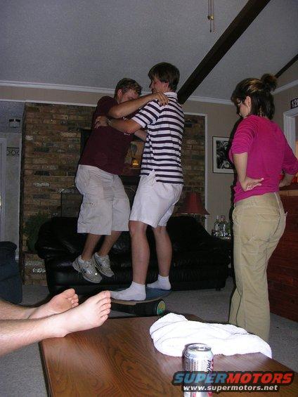 People wrestling indoors, with a can and towel on a table