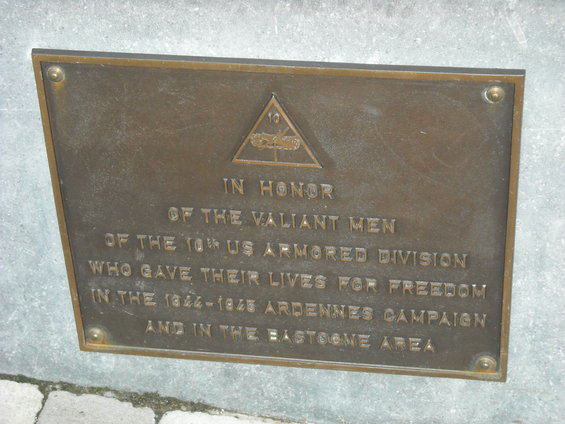 Bronze plaque with text 'IN HONOR OF THE VALIANT MEN OF THE 10TH US ARMORED DIVISION WHO GAVE THEIR LIVES FOR FREEDOM IN THE 1944-1945 ARDENNES CAMPAIGN AND IN THE BASTOGNE AREA'