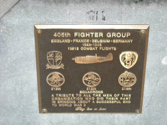 Bronze plaque with text about the 406th Fighter Group, showing an airplane and squadron emblems