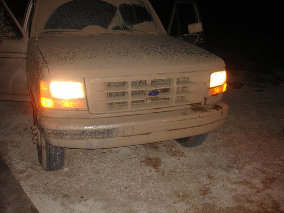 1992 Ford F-350 front end covered in mud, headlights on