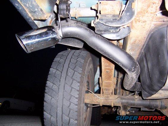 Close-up of a chrome exhaust tip and tire on a vehicle