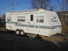 1996 Dodge 2500 - A white travel trailer with blue stripes and 'PRISM ULTRA' badging is parked on a gravel lot.