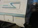 1996 Dodge 2500 - The rear corner of a Thor Prism Ultra RV shows damage and handwritten numbers on its exterior.