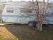 1996 Dodge 2500 - A white travel trailer with teal accents is partially obscured by a tree.