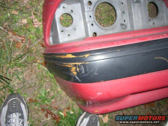 Close-up of a red car bumper with a black trim piece that is scuffed and yellowed underneath