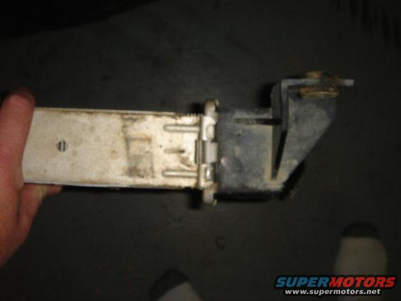 Hand holding a dirty white and black radiator part with metal clips