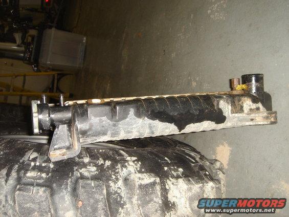 Radiator resting on a large tire. Water stains visible on the radiator