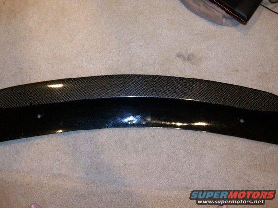 Carbon fiber and black car spoiler with two mounting holes visible