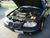 1997 Pontiac Grand Am - The engine bay of a black car is shown with the hood open.