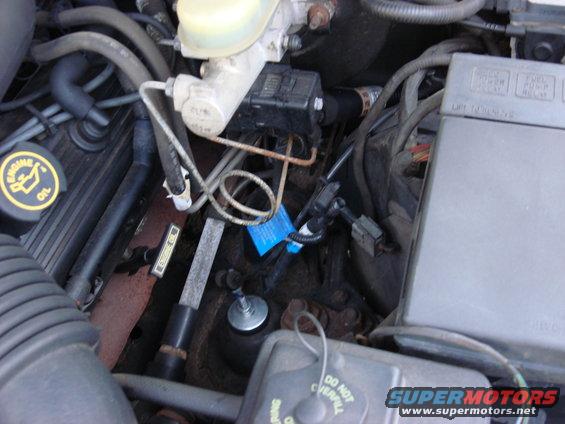 Engine bay showing brake fluid reservoir, hoses, and wiring. Includes a yellow engine oil cap