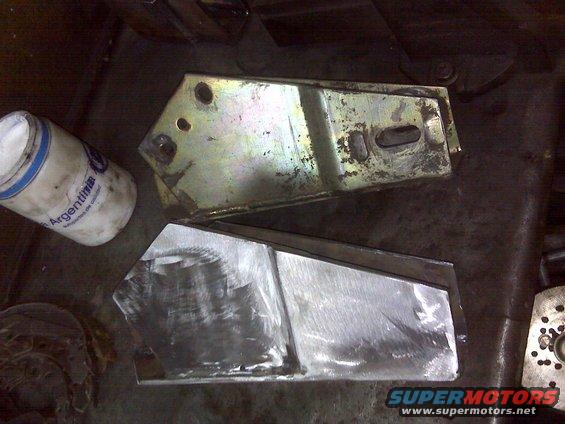 Two metal lift kit components, one with yellowing finish, the other raw metal